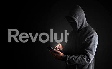 O persoană cu identitatea ascunsă care tastează pe telefon și logo-ul Revolut.